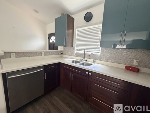 A kitchen with dark wood cabinets and a stainless steel dishwasher.