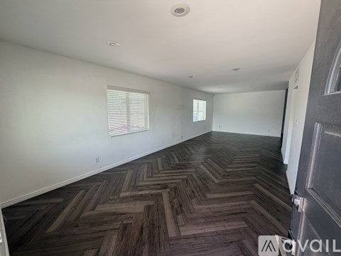 A room with wooden flooring and a window with blinds.