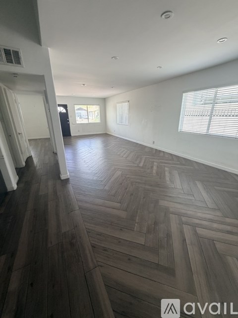 A spacious room with wooden flooring and white walls.