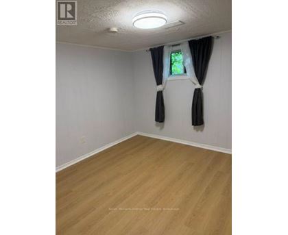A room with wooden flooring and a window with curtains.