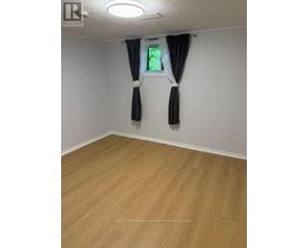 A room with wooden flooring and a window with black curtains.