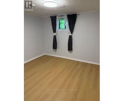 A room with wooden flooring and a window with black curtains.