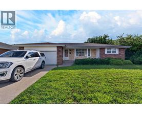 A white car is parked in front of a house with a sign that says REALTOR.
