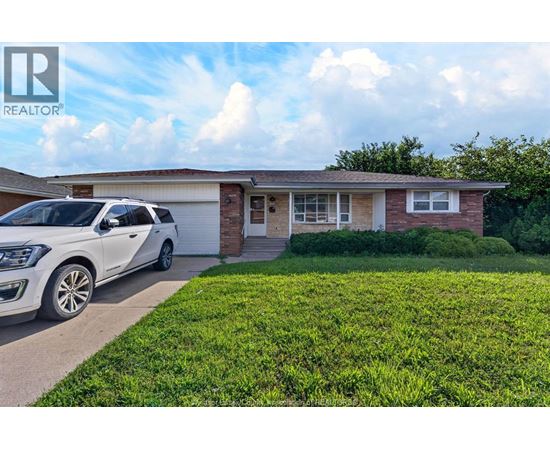 A white car is parked in front of a house with a sign that says REALTOR.