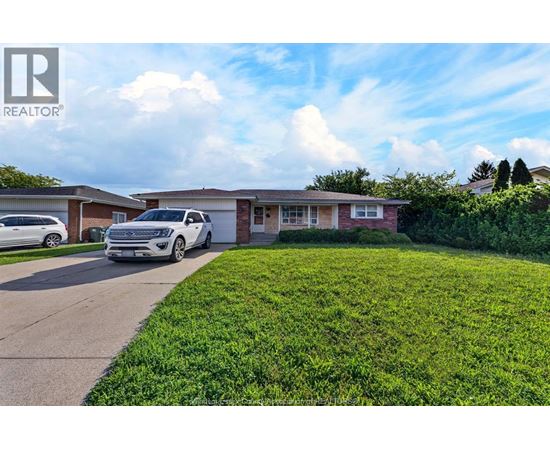 A white car is parked in front of a house with a lawn.
