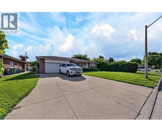 A white car is parked in a driveway in front of a house.
