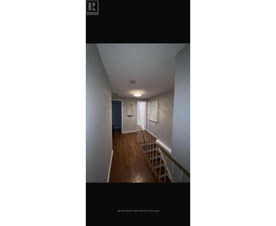 A hallway with a wooden floor and white walls.