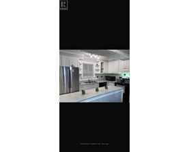 A kitchen with white cabinets and a stainless steel refrigerator.