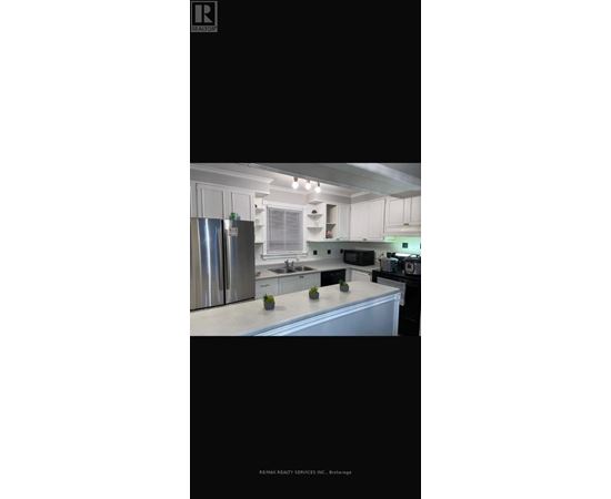 A kitchen with white cabinets and a stainless steel refrigerator.