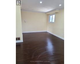 A room with a window and a wooden floor.