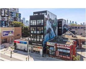 A street view of a city with buildings, a storefront, and a mural on the side of a building.