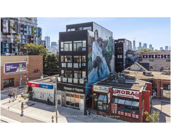 A street view of a city with buildings, a storefront, and a mural on the side of a building.