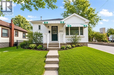 A white house with a green door and a striped awning.