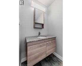 A bathroom with a sink, mirror and wooden drawers.