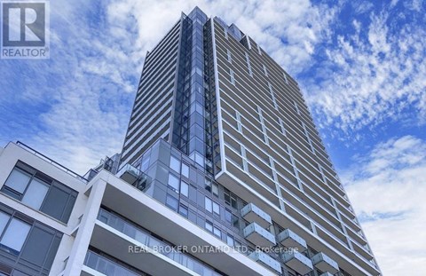 A tall building with a blue sky and clouds in the background.