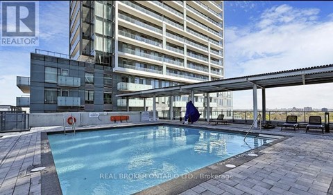A swimming pool area in front of a multi-story residential building.