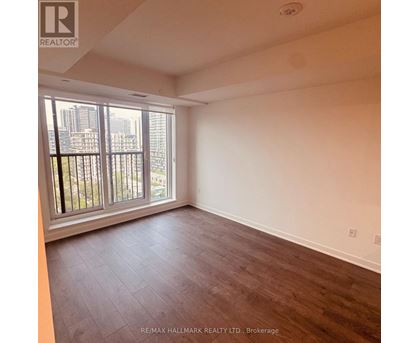 A spacious room with a large window and wooden flooring.