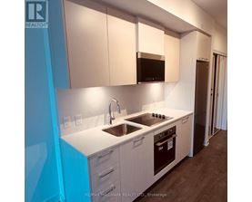 A kitchen with white cabinets and a black microwave.