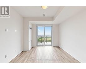 A spacious room with a sliding glass door leading to a balcony.