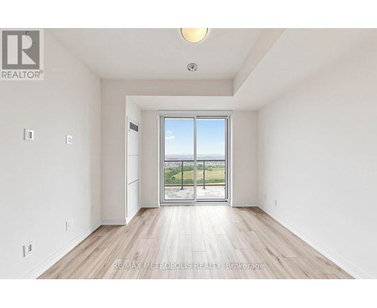 A spacious room with a sliding glass door leading to a balcony.