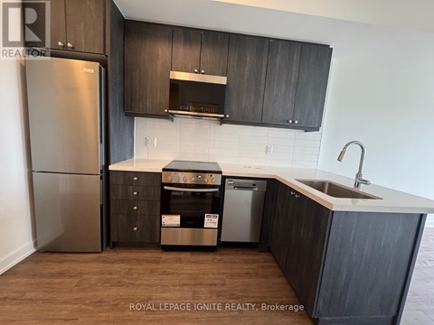 A kitchen with dark wood cabinets and a stainless steel refrigerator.