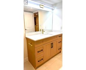 A bathroom with a sink and wooden cabinets.