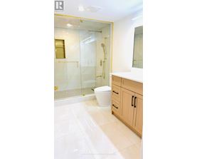 A white toilet sits in a bathroom with a walk-in shower.