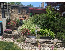A garden with a stone wall and a house in the background.