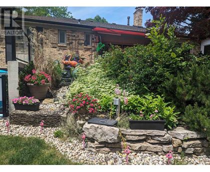 A garden with a stone wall and a house in the background.