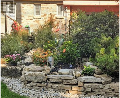 A garden with a stone wall and a variety of plants.