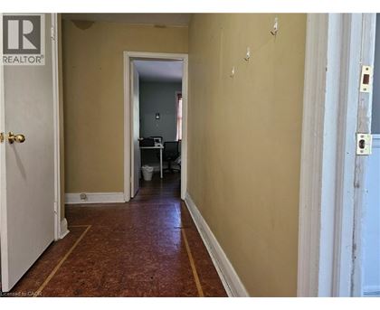 A hallway with a door on the left and a doorway in the distance.