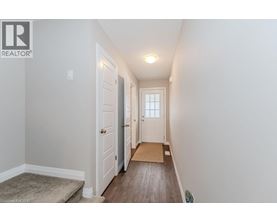 A hallway with a rug and a door on the left.
