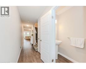 A white door is open to a hallway with a toilet and a towel hanging on the wall.
