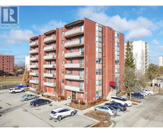 A red brick apartment building with cars parked in front.