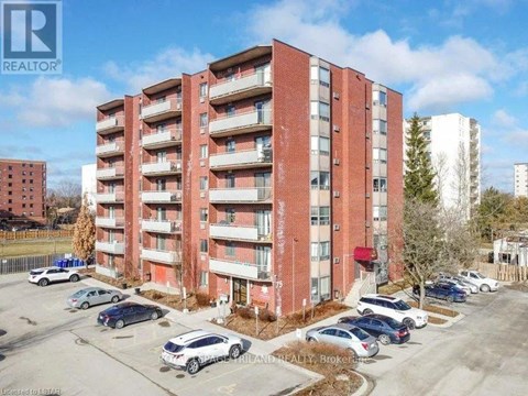 A red brick apartment building with cars parked in front.
