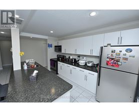 A kitchen with a refrigerator covered in magnets and a counter with a tissue box and napkins.
