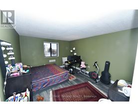 A bedroom with a bed, chair, and guitar.