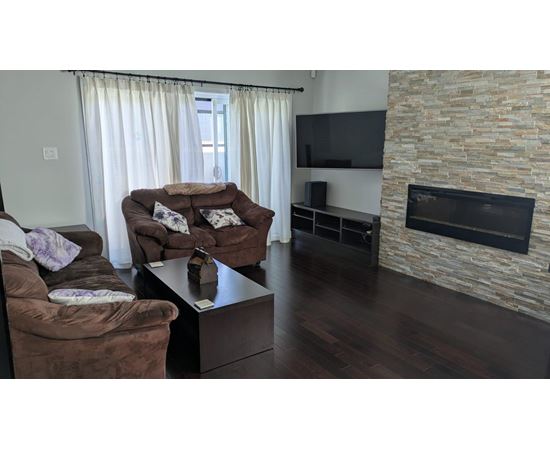 A living room with a brown couch and a stone fireplace.