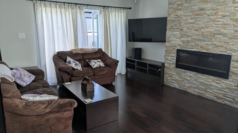 A living room with a brown couch and a stone fireplace.