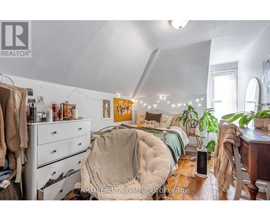 A bedroom with a bed covered in a blanket and a dresser with clothes hanging on it.