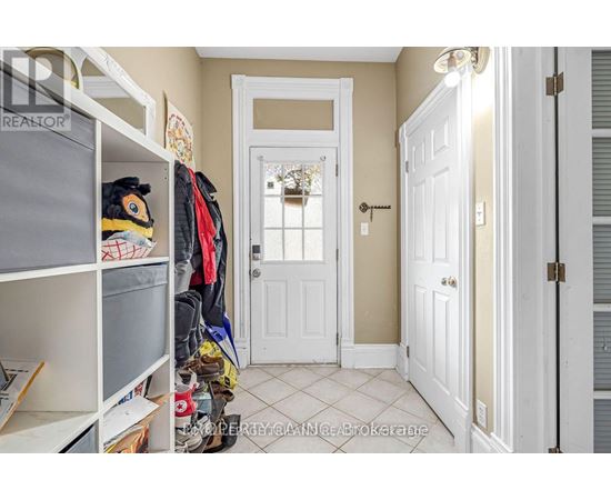 A hallway with a white door and a white closet with clothes hanging.