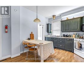 A kitchen with a table and chairs in the foreground and a stove top oven in the background.