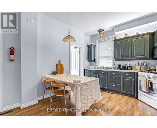 A kitchen with a table and chairs in the foreground and a stove top oven in the background.