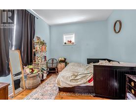 A bedroom with a bed, a chair, and a mirror.