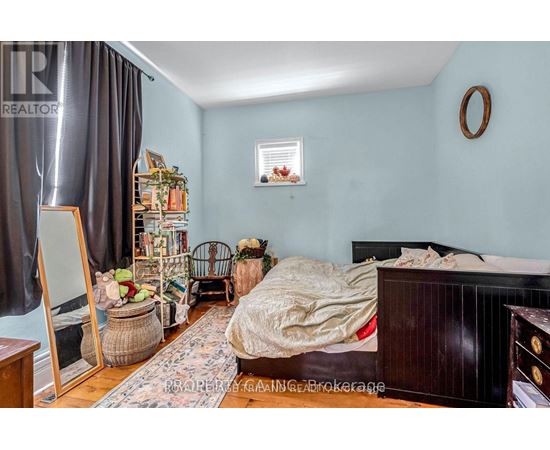 A bedroom with a bed, a chair, and a mirror.