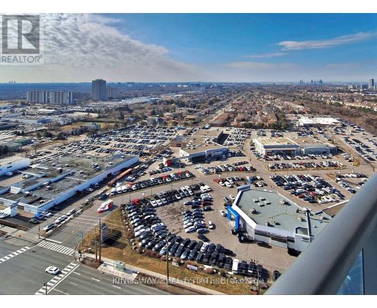 A large parking lot with several cars and buildings in the distance.