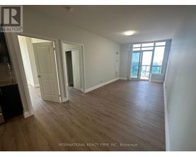 A room with wooden flooring and white walls, with a door leading to a balcony.