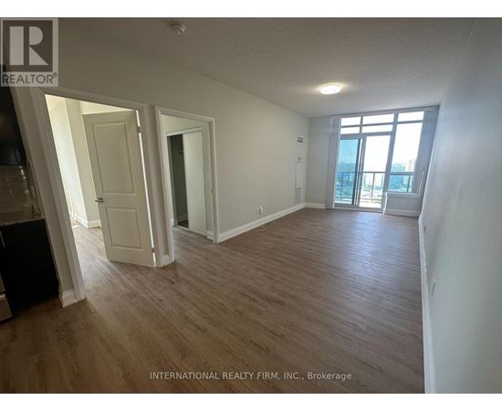 A room with wooden flooring and white walls, with a door leading to a balcony.