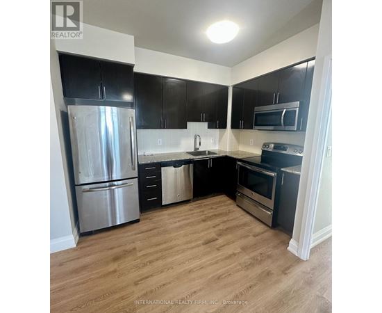 A kitchen with a refrigerator, oven, and microwave.