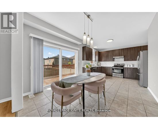 A modern kitchen with a dining table and chairs in the foreground and a balcony with a view of houses in the background.
